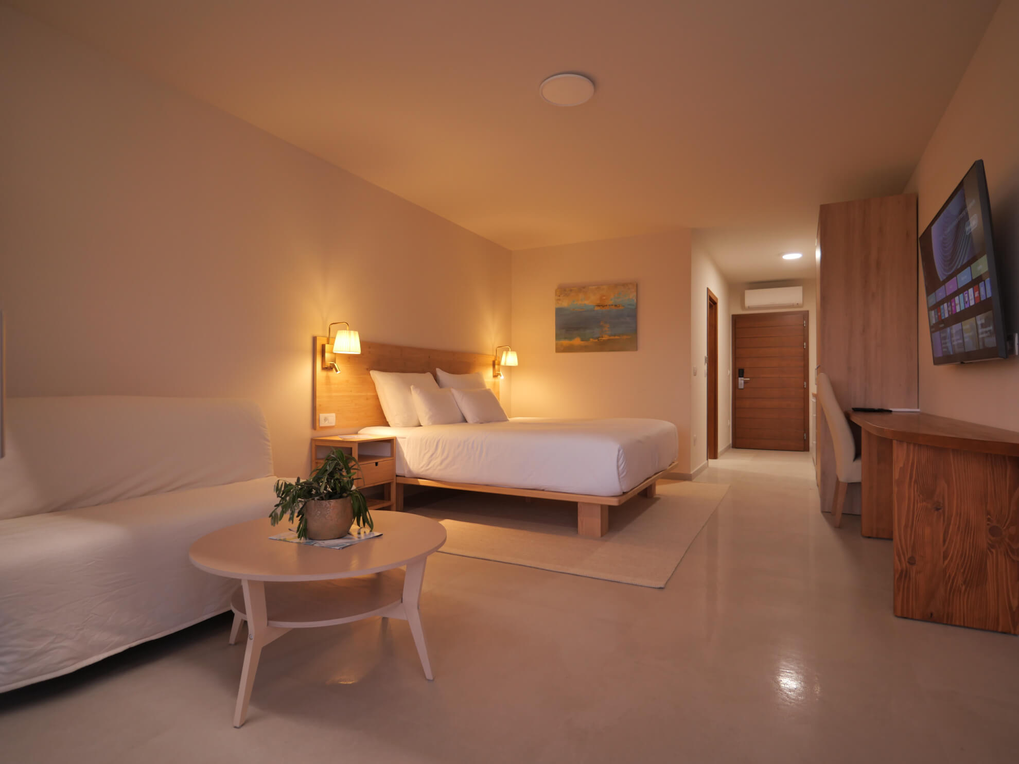 Double sized bed with couch, coffe table and television