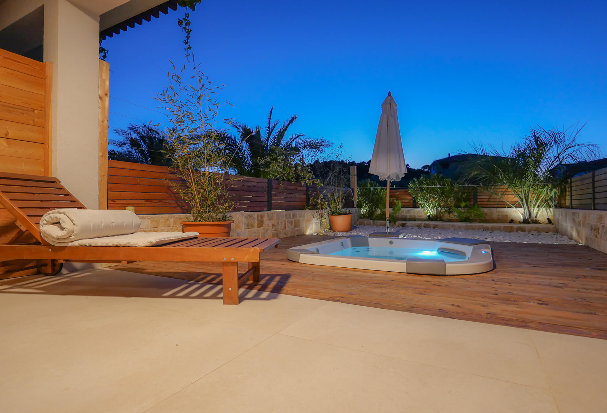 View of outside jacuzzi in sunset from lighted terrace